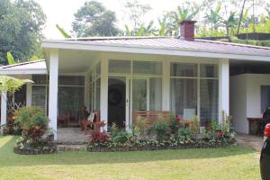 una casa blanca con porche y algunas plantas en The Forest Villa, en Bogor