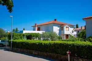 a hedge in front of a house and a parking lot at Apartment Duka in Krk