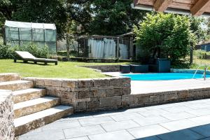 a swimming pool with a stone retaining wall and a bench at Ferienhaus erholzeit. in Wettringen