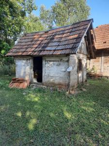un vecchio edificio sull'erba vicino a una casa di Kuća za odmor Cordon a Vojnić