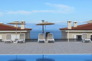 a group of chairs and umbrellas next to a pool at Luxury House with 3 Bedrooms, Sea Wiew and Swimming Pool in a quiet Residence in Puerto de Santiago