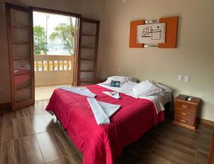 a bedroom with a bed with a red blanket and a window at Beira Mar in Ubatuba