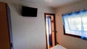 een kamer met een tv aan de muur en een raam bij la casetta da paola in Bardalone