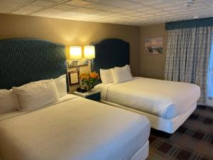 a hotel room with two beds with white sheets at King's Port Inn in Kennebunkport