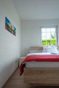 a bedroom with a bed with a red blanket and a window at Pannonia Lake House in Neusiedl am See