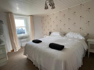 um quarto com uma cama branca com duas toalhas pretas em Forty Five, John Street, Stromness, em Stromness