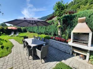 a patio with a table and an umbrella and a grill at Chalet Landhaus Einsiedler in Sankt Gallenkirch
