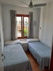 two beds in a room with a window at Apartamento en Arenal a 5 minutos de la playa in Arenal d'en Castell