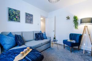 ein Wohnzimmer mit einem blauen Sofa und einem Stuhl in der Unterkunft Spacious 2-Bed City-Centre Cottage in Chester by 53 Degrees Property - Ideal for Groups & Couples - Sleeps 6 in Chester