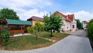 a house with a walkway in front of a yard at White Apartment in Keszthely