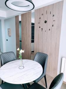 a white table with chairs and a clock on a wall at AVENUE APARTMENTS-Hermes in Chişinău