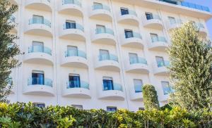 an apartment building with balconies and trees at Ghibli Boutique Hotel Civitanova Marche in Civitanova Marche