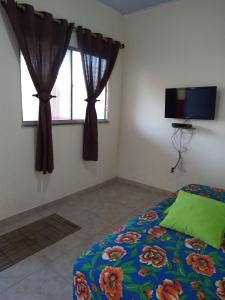 Schlafzimmer mit einem Bett und einem Fenster mit Vorhängen in der Unterkunft Cantinho da Paz in Ilhéus
