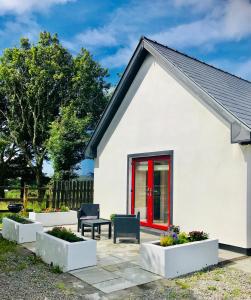 una casa blanca con una puerta roja y algunas plantas en Red Deer Cosy Apartment in Letterfrack Connemara, en Letterfrack