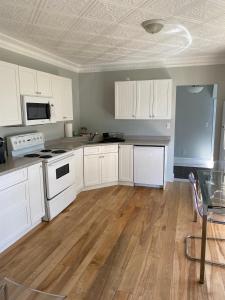 a kitchen with white cabinets and a wooden floor at Breakwater Lodge in Lower Woods Harbour