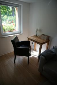 ein Wohnzimmer mit einem Stuhl, einem Tisch und einem Fenster in der Unterkunft Ferienwohnung Lorbeer in Meißen