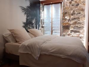 a bed in a bedroom with a stone wall at Charmant appartement, centre piéton Vieille Ville Annecy in Annecy