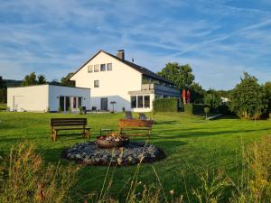 uma grande casa branca com uma fogueira no quintal em MUT.HAUS em Bischofsheim an der Rhön