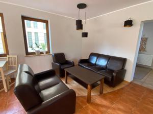 a living room with leather furniture and a table at Willa Mare in Dębki