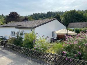 a white house with a garden in front of it at Ferienhaus Hunsrückliebe mit privater Außensauna in Liederbach