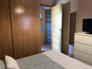 um quarto com uma cama, um closet e uma televisão em Casita rural acogedora em Combarro