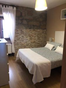 1 dormitorio con 2 camas y pared de ladrillo en Casita rural acogedora, en Combarro