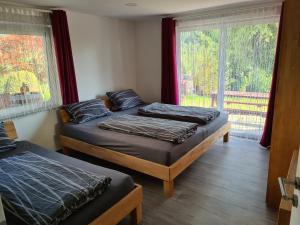 two beds in a room with a window at 'Tor zum Schwarzwald' Ferienwohnungen mit Sauna in Wildberg