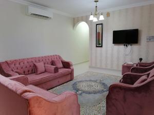een woonkamer met 2 banken en een tv bij Sur Inn Hotel Apartments صور ان للشقق الفندقية in Sur