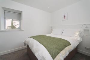 a white bedroom with a bed and a window at The Stable - The Cottages at Blackadon Farm in Ivybridge