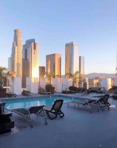 a pool with chairs and a city skyline in the background at Huge Downtown LA Loft with Rooftop Pool & Jacuzzi in Los Angeles