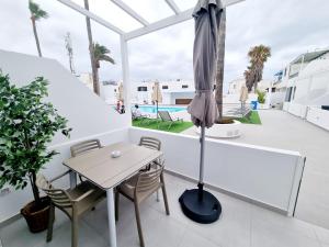 a table and chairs on a balcony with an umbrella at Luxury Zen Puerto Del Carmen in Puerto del Carmen