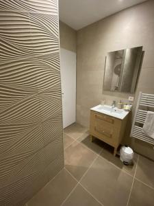 ein Bad mit einem Waschbecken und einem Spiegel in der Unterkunft Appart’hôtel les perles du lac in Tombeboeuf