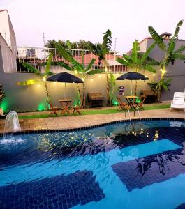 una piscina con mesas y sombrillas en una casa en Hostel Praia Centro Itanhaém, en Itanhaém