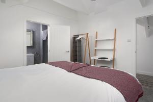 - une chambre avec un lit blanc et une couverture violette dans l'établissement The Loft - The Cottages at Blackadon Farm, à Ivybridge