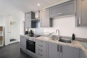 a kitchen with white cabinets and a sink at The Loft - The Cottages at Blackadon Farm in Ivybridge
