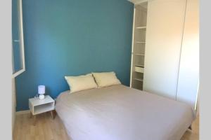 - une chambre avec un lit blanc et un mur bleu dans l'établissement Paisible maison entre plages, lacs et bassin, à Le Porge