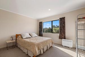 a bedroom with a bed and a window at Lake View Hideaway - Kuratau Holiday Home in Kuratau