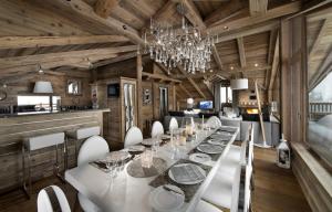 a dining room with a long table and white chairs at Les 3 Chalets Courchevel in Courchevel