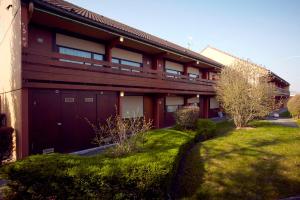 un bâtiment rouge avec un garage et une pelouse dans l'établissement Kyriad Châlons-En-Champagne - Saint-Martin, à Saint-Martin-sur-le-Pré