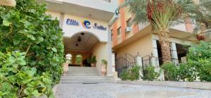 a building with stairs and a palm tree in front of it at Elite Suites Hurghada in Hurghada