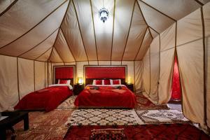 a bedroom with two beds in a tent at Desert camp camel & sandboarding in Merzouga