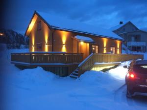 ein Haus mit einem Auto, das nachts im Schnee geparkt ist in der Unterkunft Margithuset in Reine