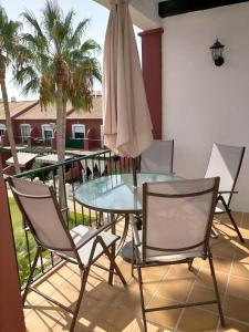 patio ze szklanym stołem, krzesłami i parasolem w obiekcie Coto la Campa w mieście Chiclana de la Frontera
