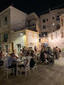 Un grupo de personas sentadas en mesas frente a un edificio. en Casa Buena Vida (locazione ad uso turistico), en Monopoli