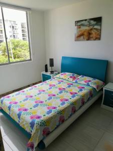 a bedroom with a bed with a colorful comforter and a window at PeñalisaKapoSalSar in Girardot