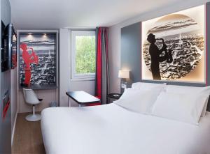 Un dormitorio con una cama blanca grande y una ventana en Hôtel Inn Design Paris Saint Quentin, en Montigny-le-Bretonneux