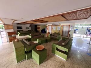an empty lobby with green chairs and tables at Conforto e Aventura Flat Lençois Barreirinhas in Barreirinhas