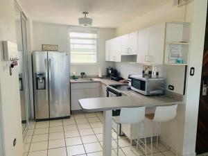 a kitchen with a stainless steel refrigerator and white cabinets at Coastal View Apartment in Ceiba