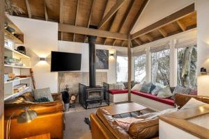 a living room with a fireplace and leather furniture at Belltrees in Dinner Plain