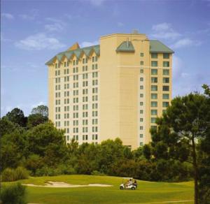 - un grand bâtiment avec une voiturette de golf devant dans l'établissement Hollywood Casino - Bay Saint Louis, à Bay Saint Louis